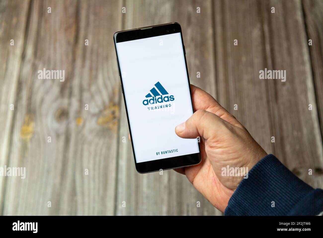 Ein Mobiltelefon oder Mobiltelefon, das in einem gehalten wird Hand mit der Adidas Training App auf dem Bildschirm geöffnet Stockfoto