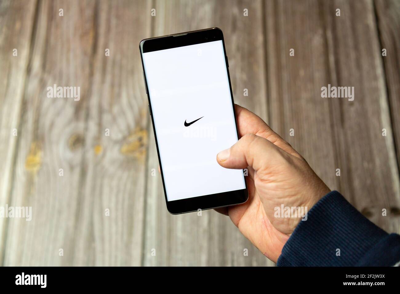 Ein Mobiltelefon oder Mobiltelefon, das in einem gehalten wird Hand mit der Nike App geöffnet auf dem Bildschirm Stockfoto