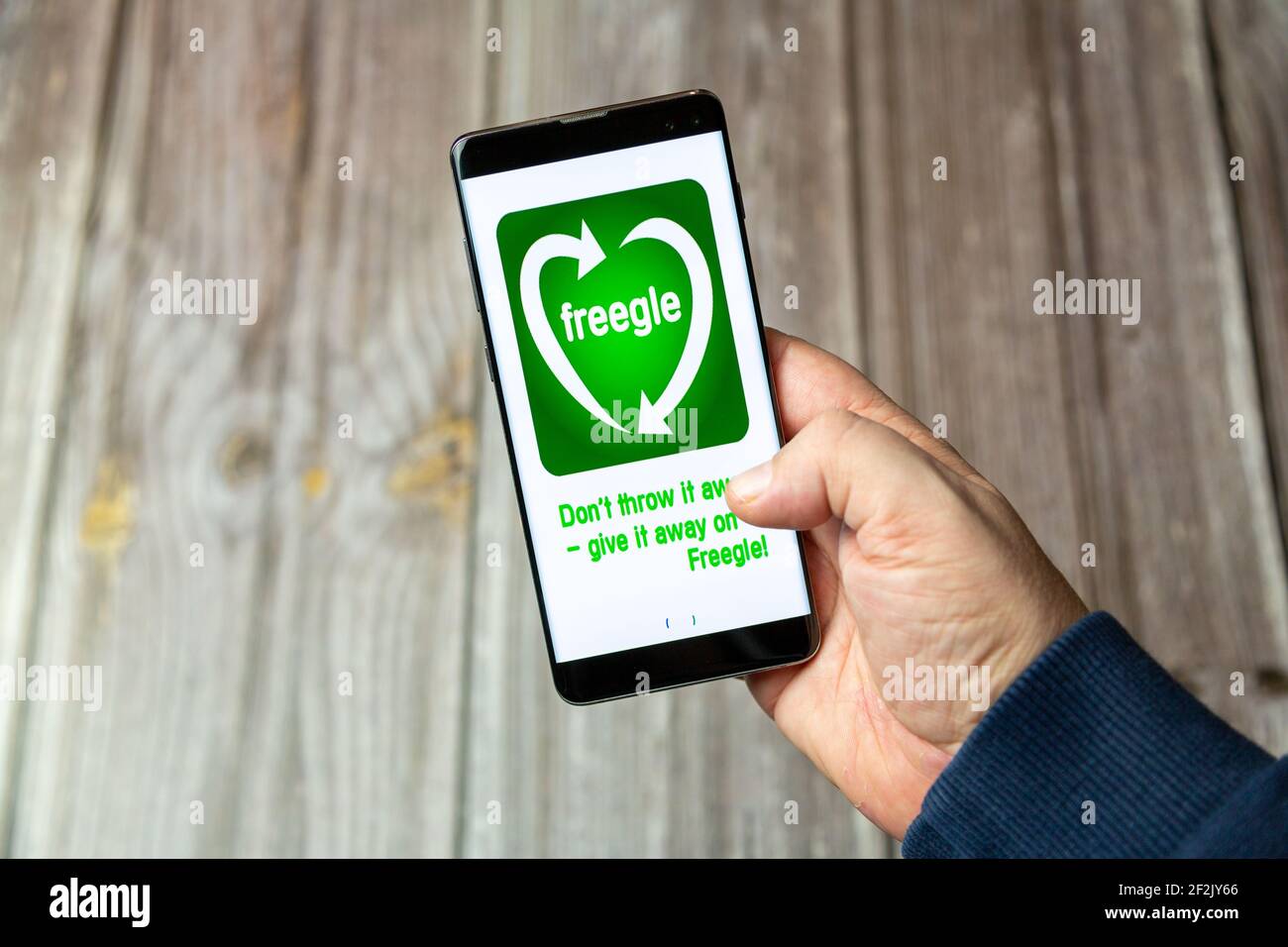 Ein Mobiltelefon oder Mobiltelefon, das in einem gehalten wird Hand mit der Freegle App auf dem Bildschirm geöffnet Stockfoto
