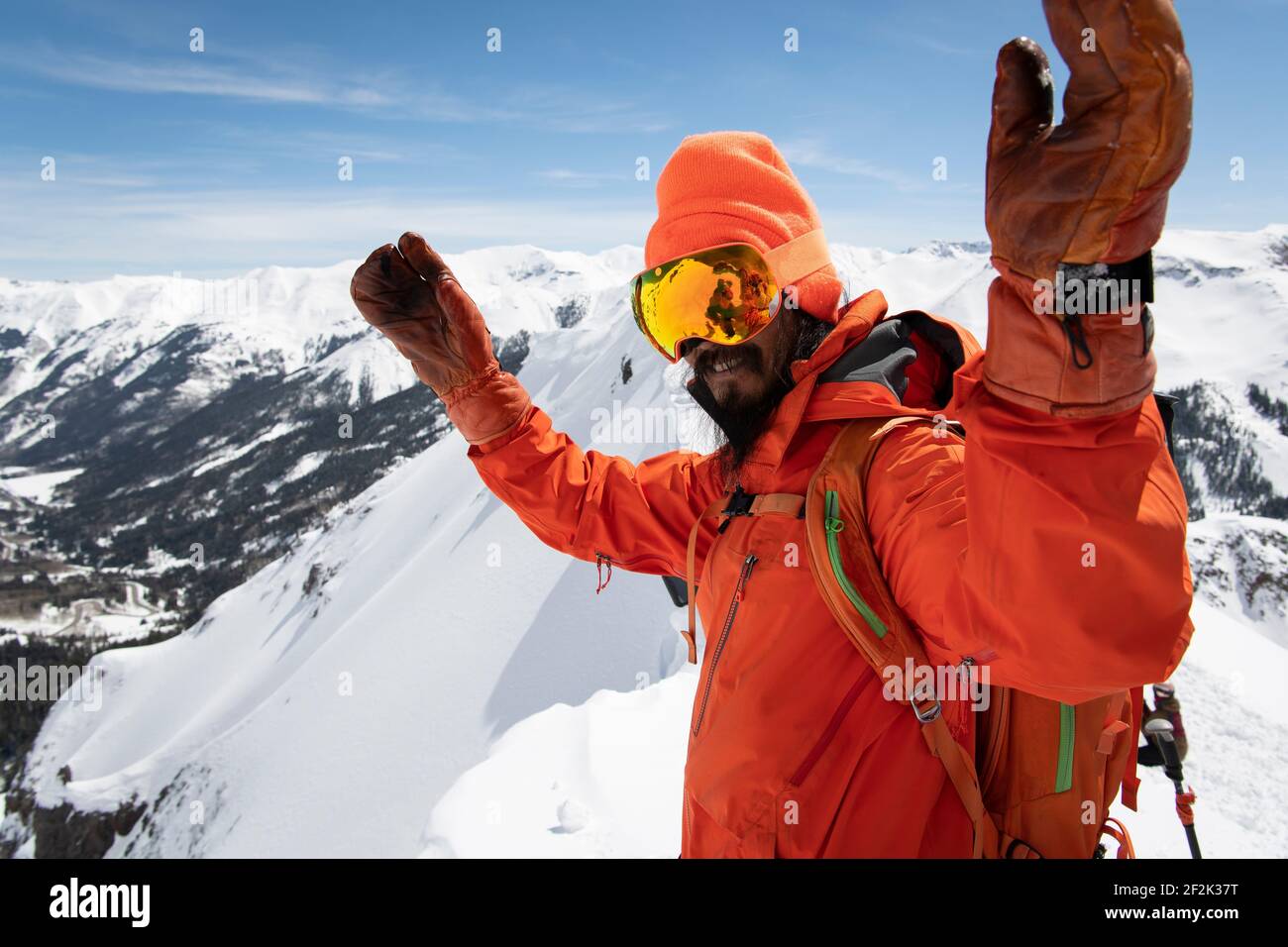 Mann in warmer Kleidung, der mit aufgehobenen Armen steht Berg Stockfoto