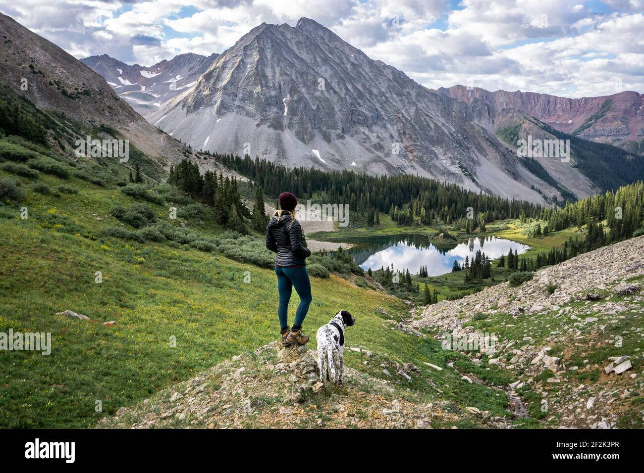 Hikerin mit Hund und Blick auf den schönen Berg Stockfoto
