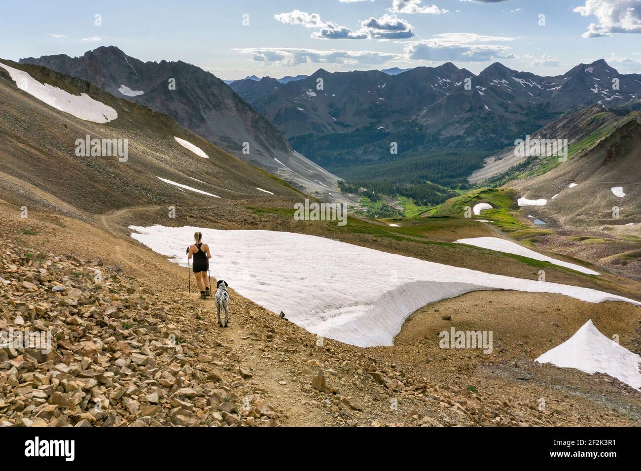 Rückansicht einer Frau, die mit Hund auf dem Berg in den Berg wandert Winter im Urlaub Stockfoto