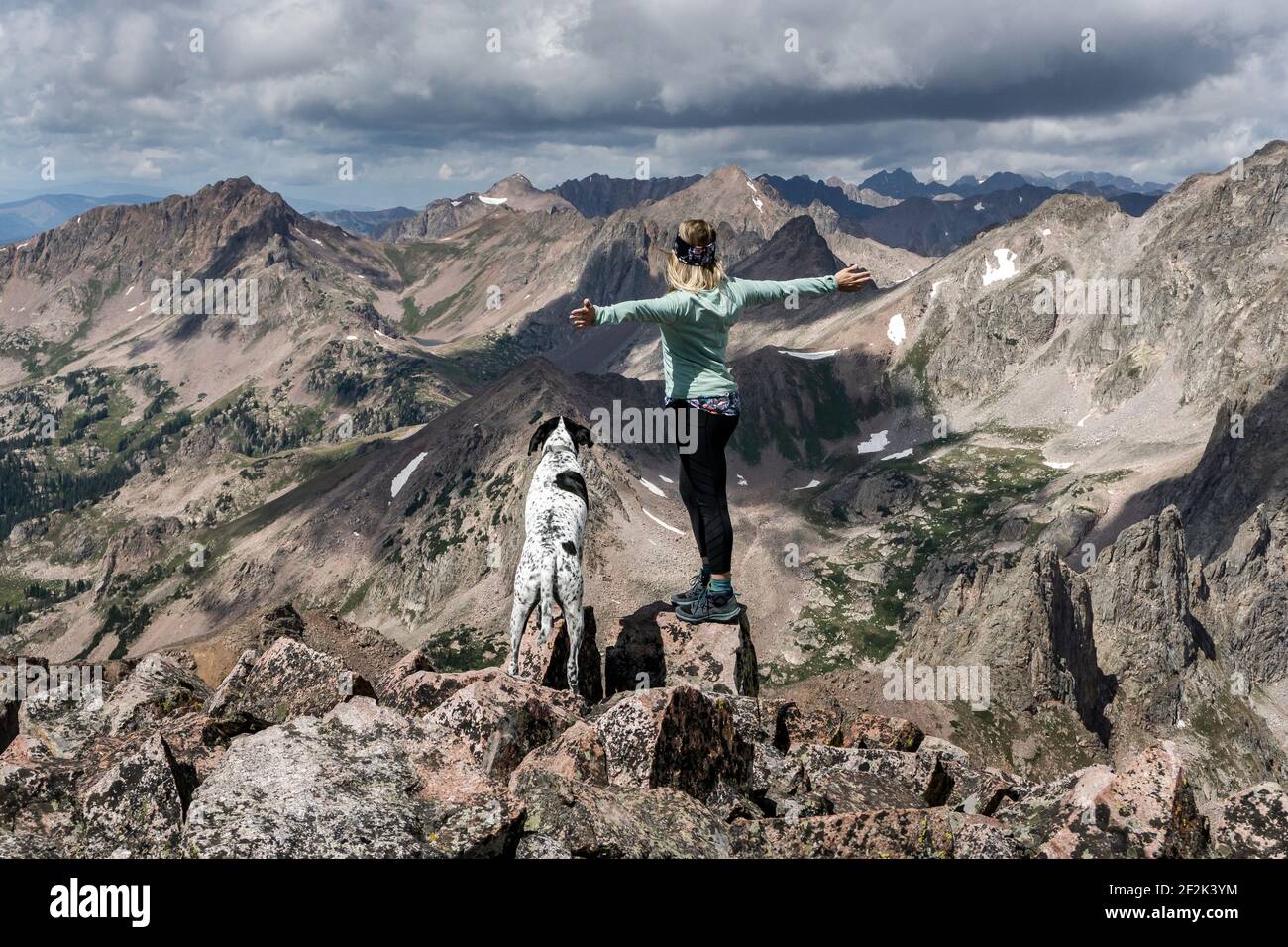 Wanderweibchen wandern mit Hund auf dem Berg gegen bewölkten Himmel Stockfoto