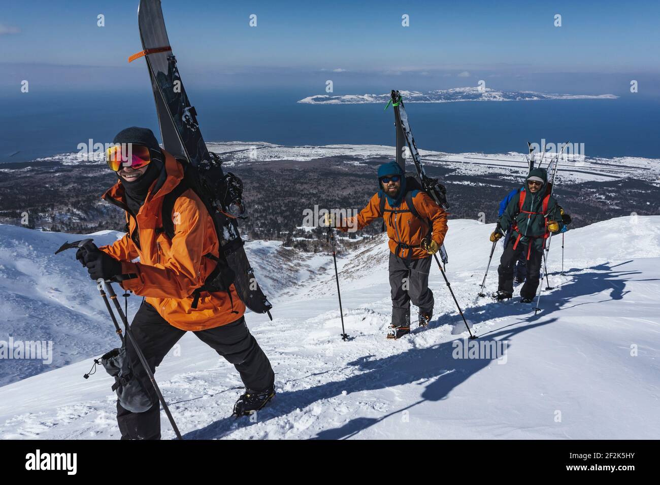 Männer mit Skistöcken klettern schneebedeckten Berg während des Urlaubs Stockfoto