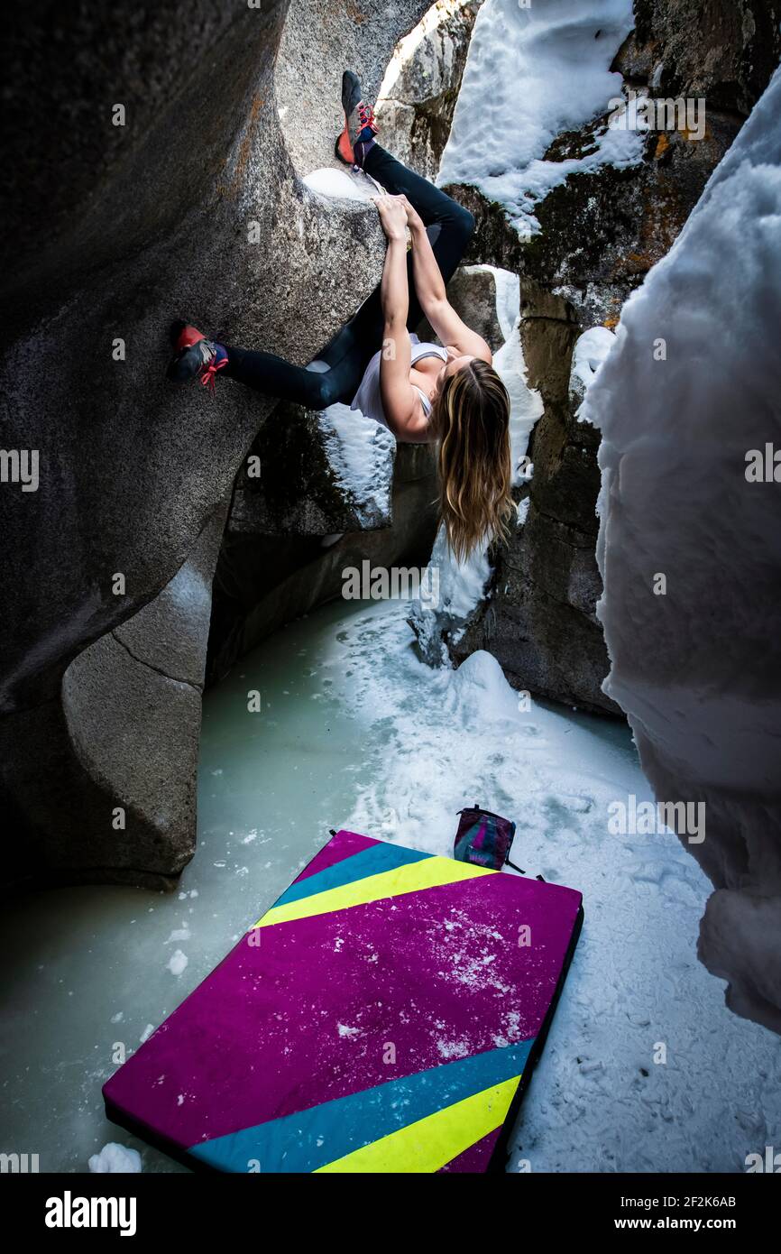 Junge Frau übt Bouldern auf Felsformationen in Eishöhlen Am Independence Pass Stockfoto