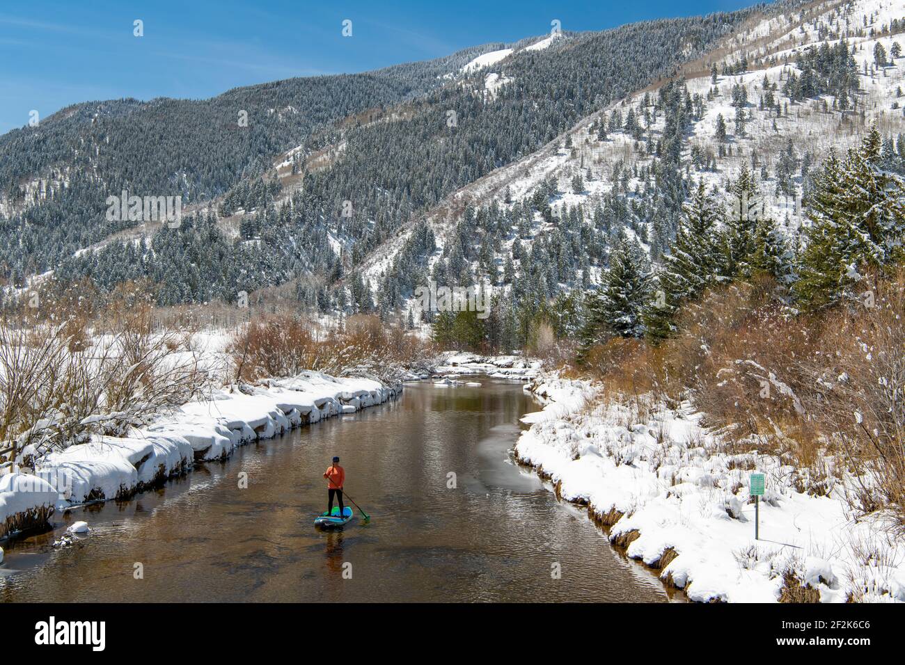 Frau paddeln auf dem Fluss im Winter Stockfoto