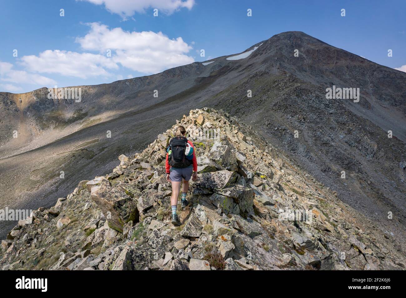 Rückansicht einer Wanderin, die auf Felsen am Berg läuft Stockfoto