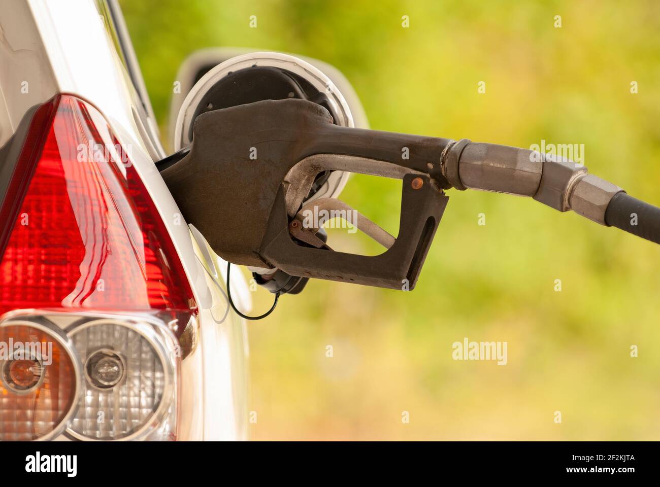 Horizontaler Schuss einer Benzindüse in der Tanköffnung eines Autos. Stockfoto