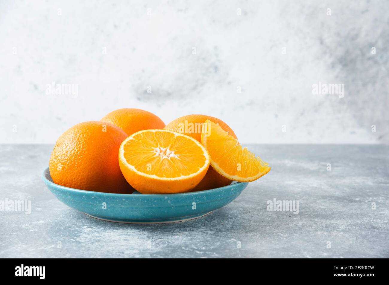 Ein Teller voller geschnittener und voller saftiger Orangenfrüchte Auf steinernem Hintergrund Stockfoto