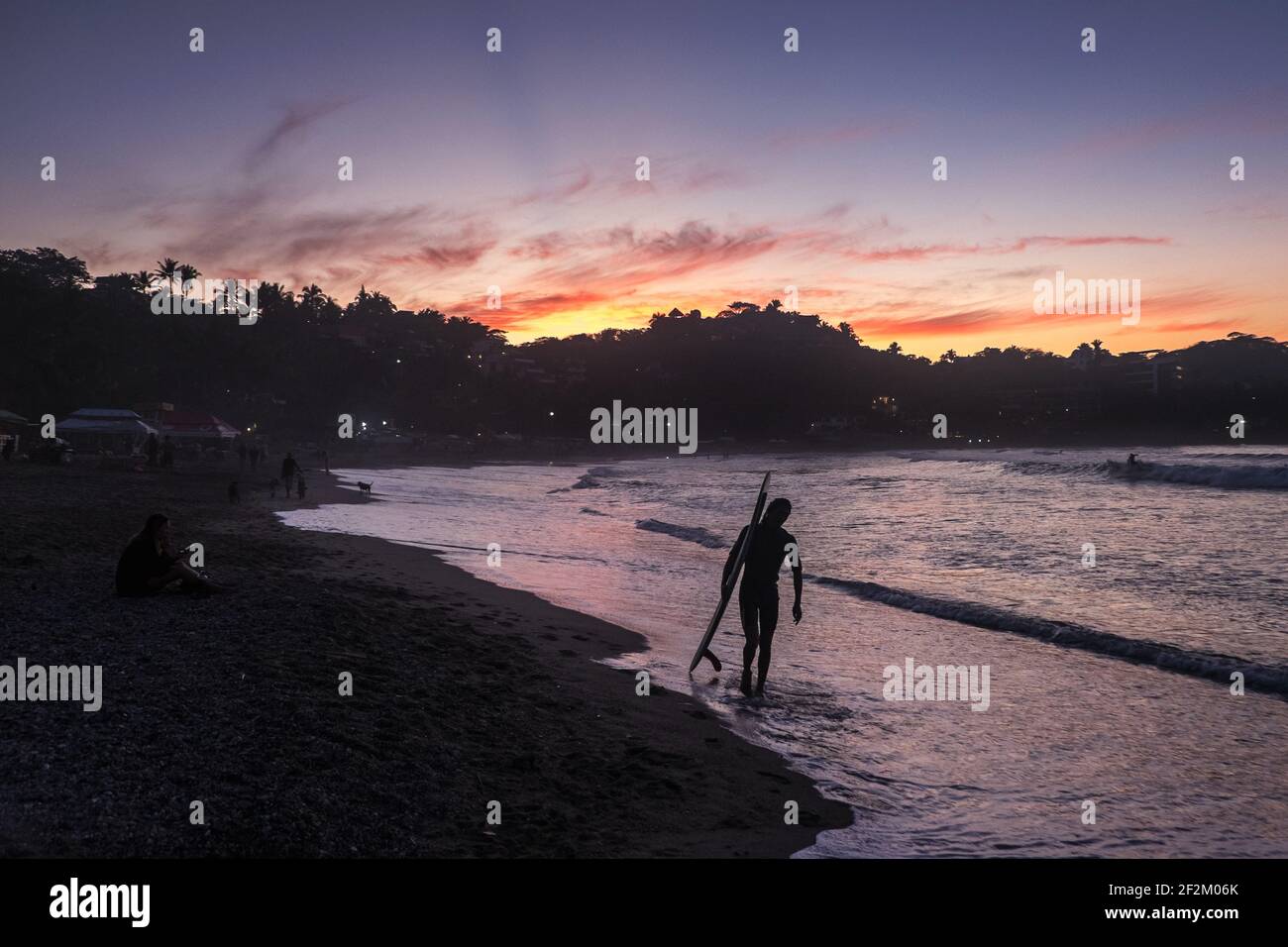 Ein Surfer geht zum Strand bei Sonnenaufgang in Sayulita, Mexiko Stockfoto