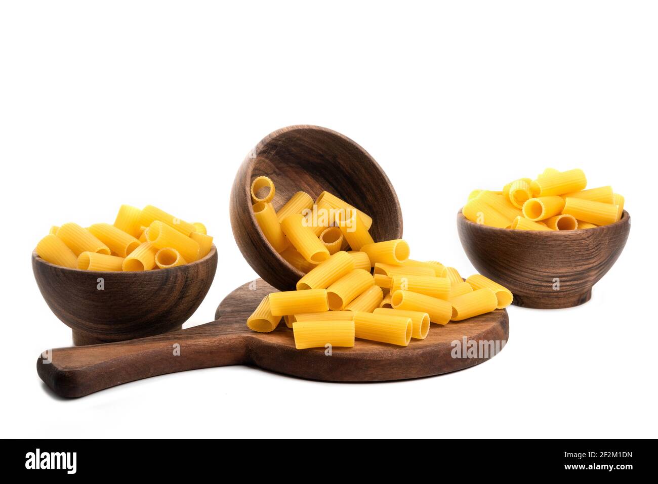 Holzschüsseln voller ungekochter, glatter, kurzer Röhren Formen Pasta Auf einem Holzbrett Stockfoto