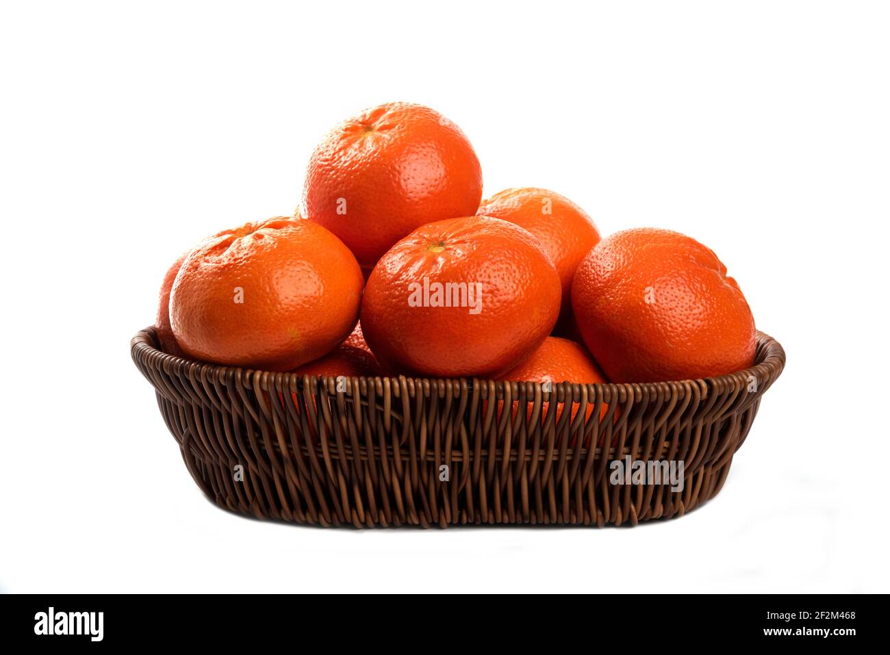 Ganze saftige frische Orangenfrüchte in einem Weidenkorb auf Ein weißer Hintergrund Stockfoto