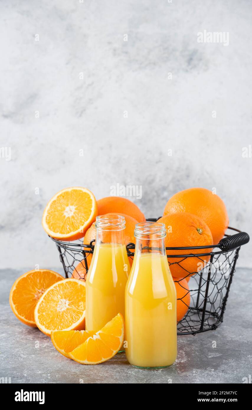 Ein Glas Krug Saft mit frischen Orangenfrüchten auf Steinhintergrund Stockfoto