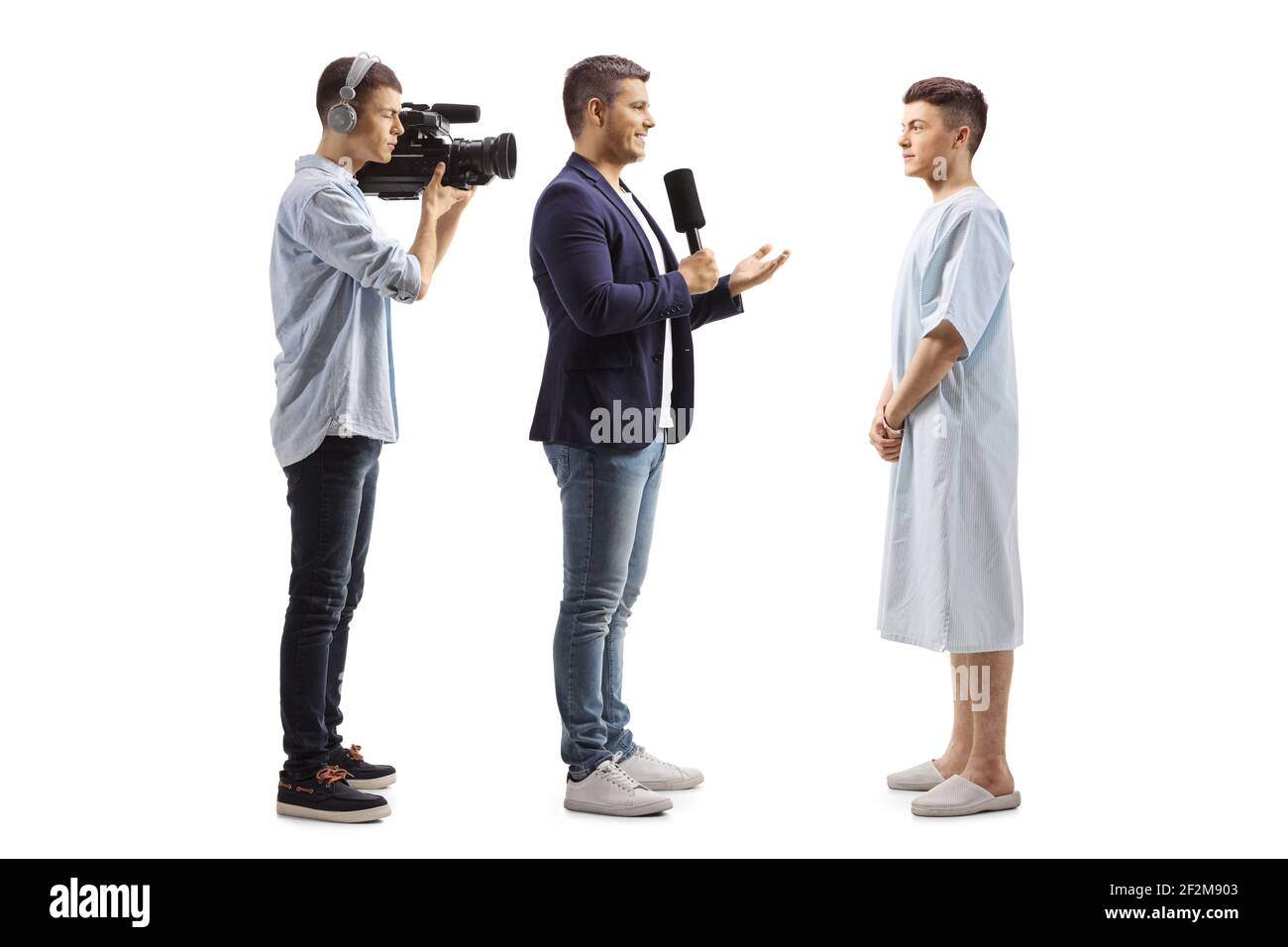 Reporter und Kameramann interviewten einen jungen männlichen Patienten Ein Krankenhauskleid isoliert auf weißem Hintergrund Stockfoto