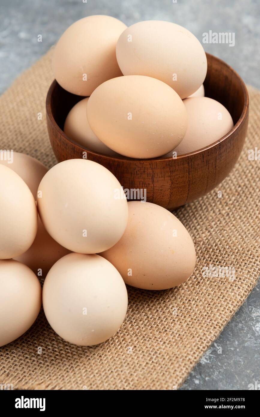 Holzschale aus Bio-rohen Eiern auf Marmoroberfläche Stockfoto