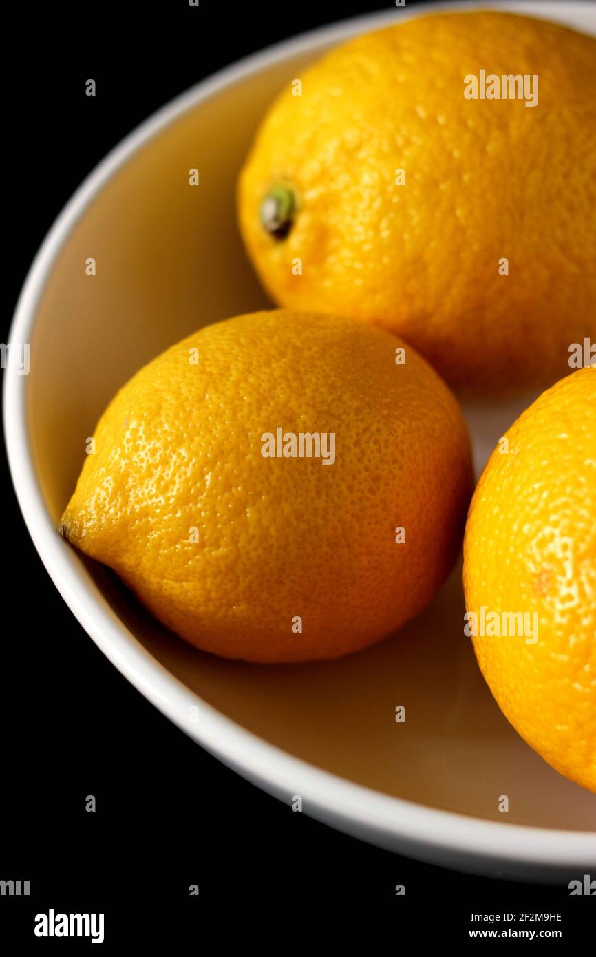 Frische Zitronen in Teller auf schwarzem Hintergrund. Reife Früchte. Stockfoto