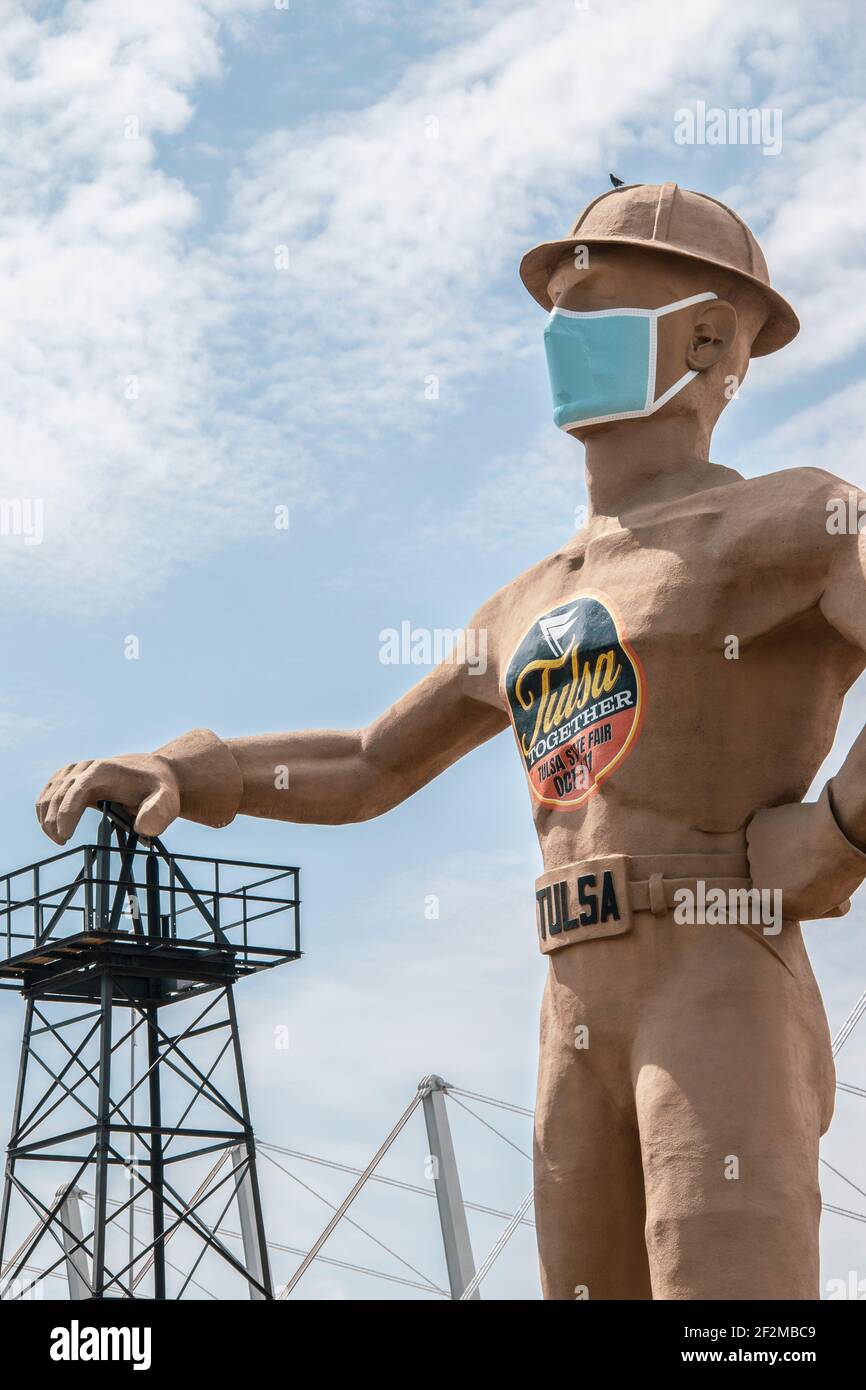07 09 2020 Tulsa, USA Iconic Golden Driller - Riesenstatue des Ölfeldarbeiters in der Nähe der Route 66 in Oklahoma mit Harthut und Gesichtsmaske mit der Hand Stockfoto