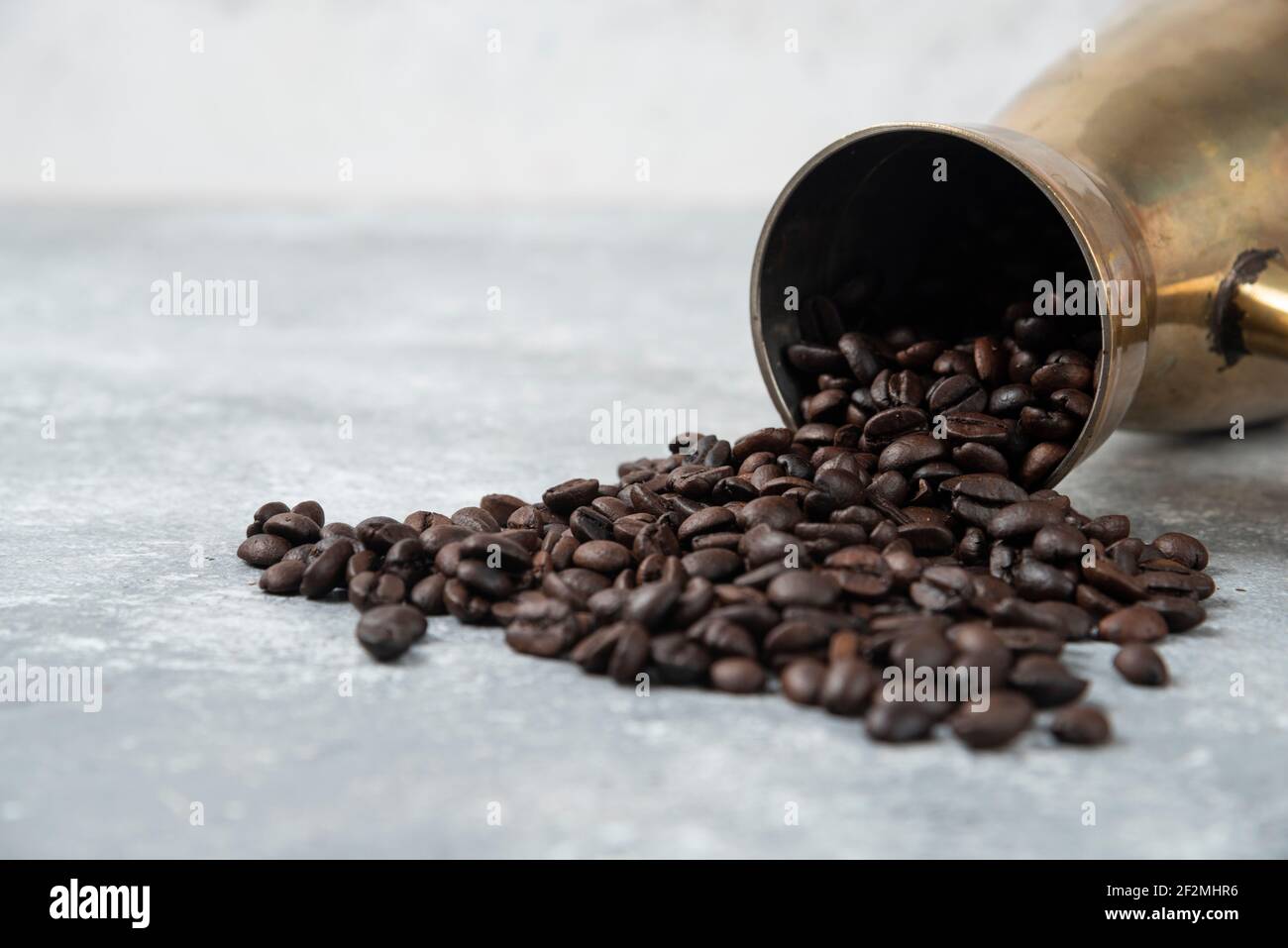 Kaffeemaschine voller gerösteter Kaffeebohnen auf Marmoroberfläche Stockfoto