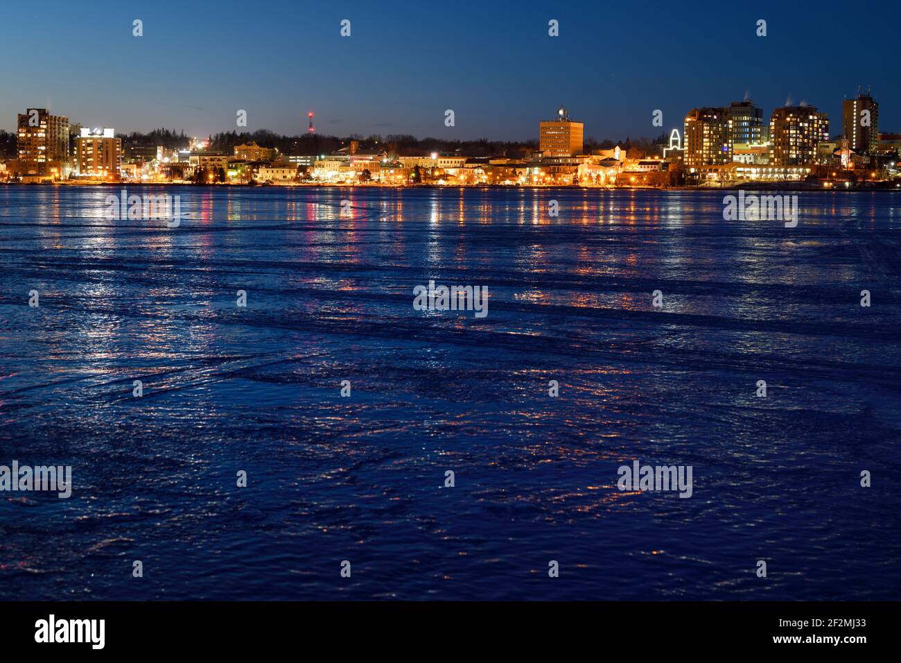Die Lichter der Innenstadt von Barrie Canada reflektierten sich auf dem Eis Gefrorene Kempenfelt Bay Lake Simcoe in einer kalten Winternacht Stockfoto