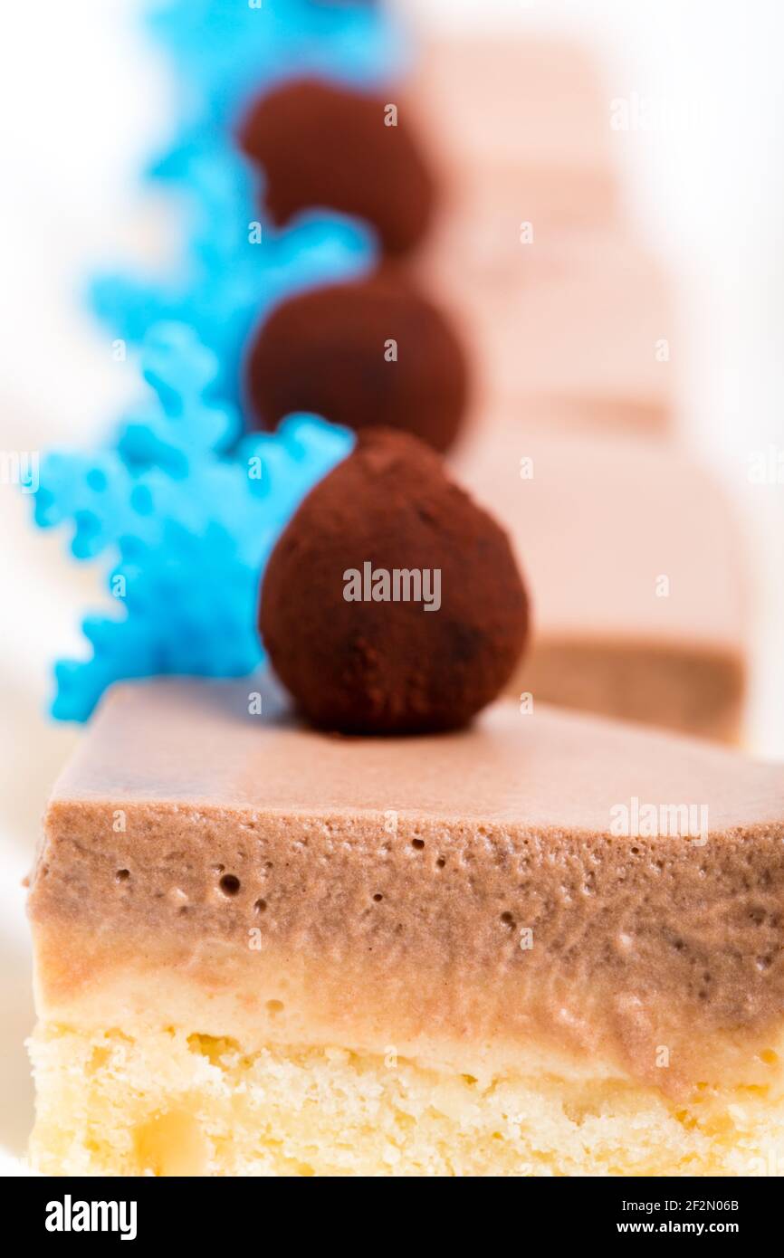 Leckere Mousse-Kuchen mit Schokoladentrüffel und blauen Mastix-Schneeflocken. Makro. Foto kann als ganzer Hintergrund verwendet werden. Stockfoto