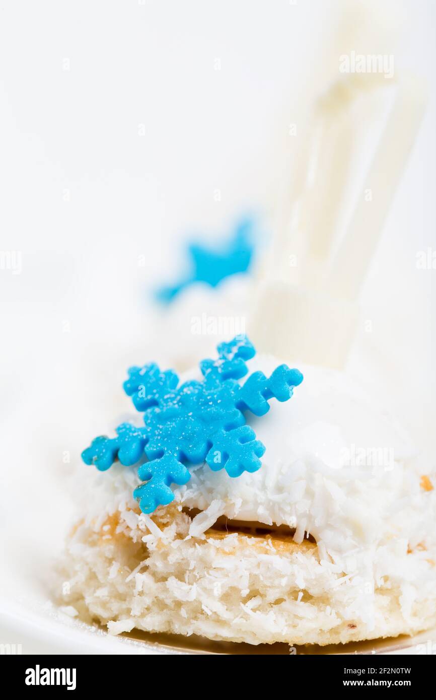 Köstliche glasierte Kuchen mit Kokosnusszuckerguss und blauen Mastix-Schneeflocken. Makro. Foto kann als ganzer Hintergrund verwendet werden. Stockfoto