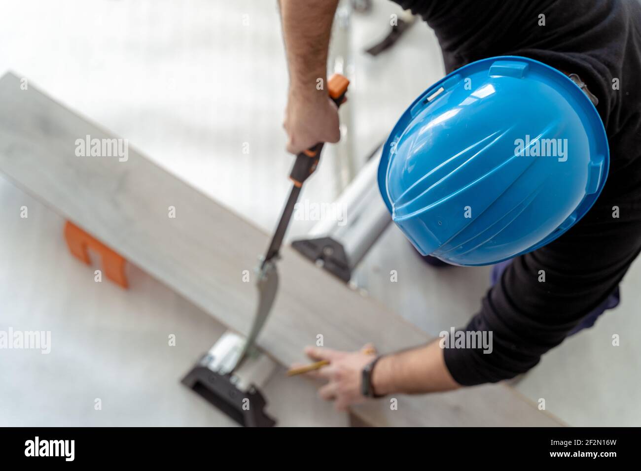 Luftaufnahme eines Zimmermanns, der ein Holzlaminat zuschneidet Installieren Sie einen Holzboden Stockfoto