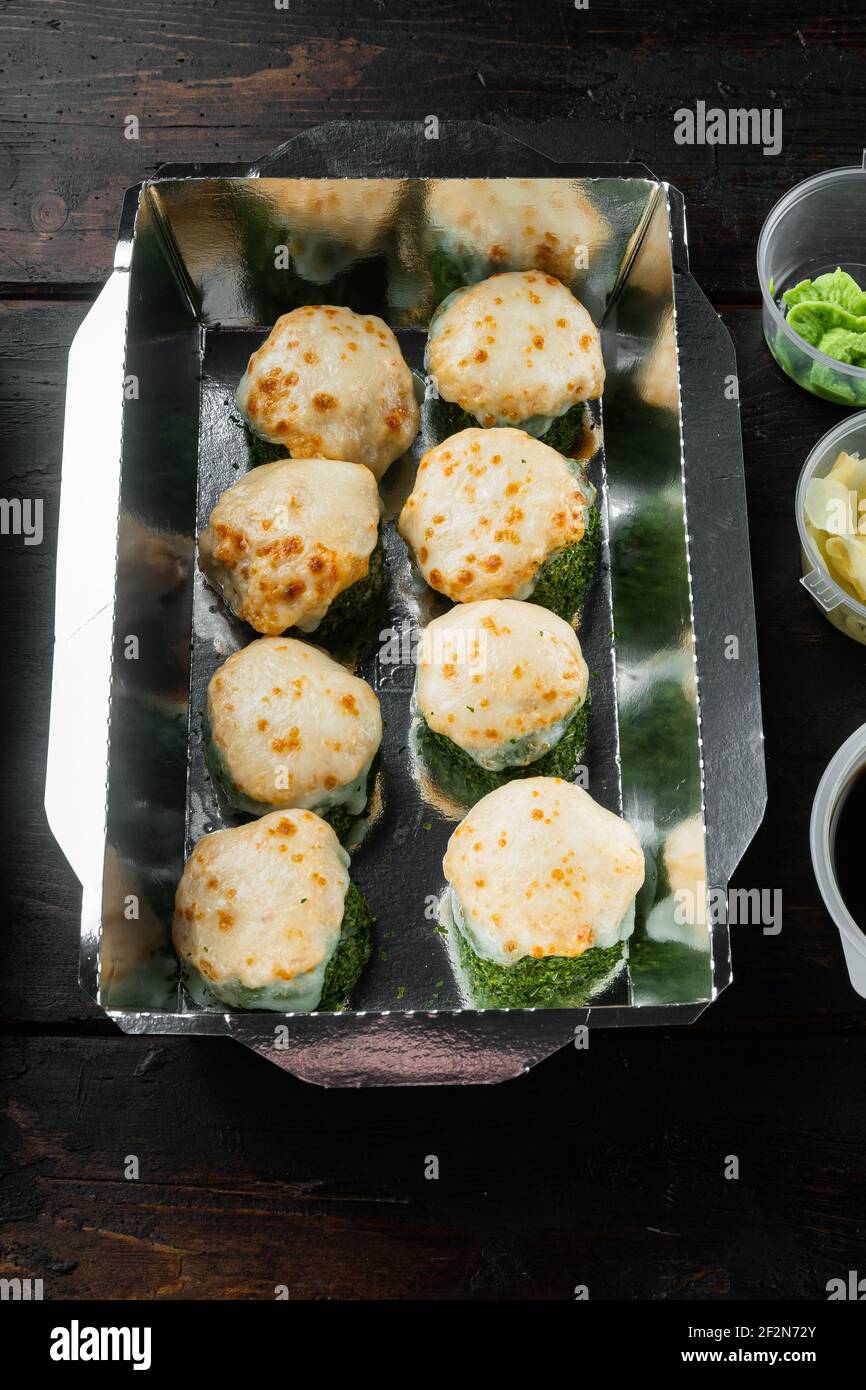 Leckere Sushi-Rollen in Einwegkisten Set, auf alten dunklen Holztisch Hintergrund Stockfoto
