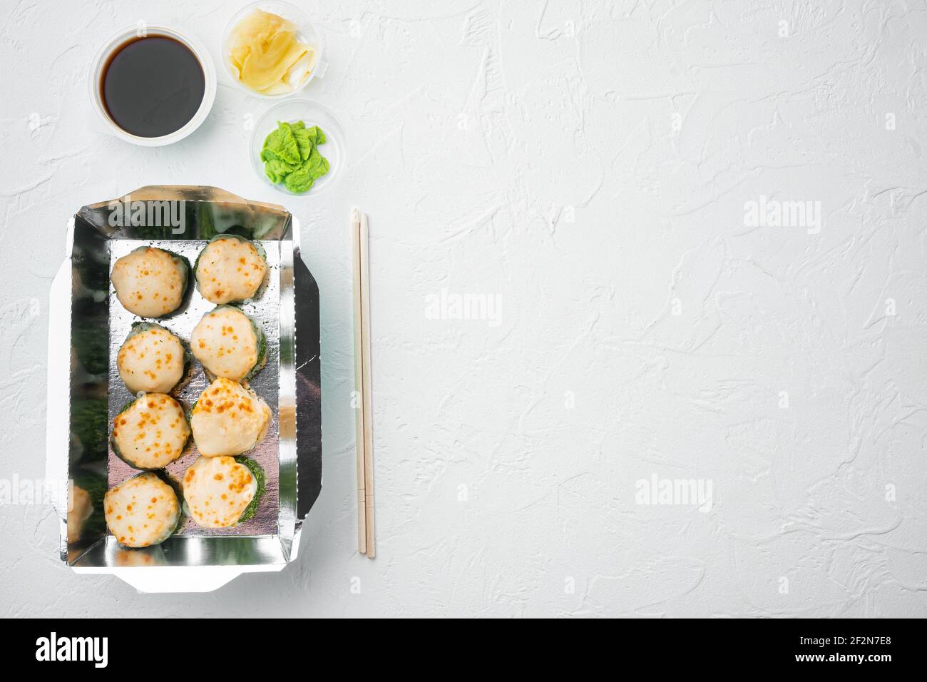 Sushi-Rollen im Takeaway-Container-Set, auf weißem Stein-Hintergrund, Draufsicht flach liegend, mit Copyspace und Platz für Text Stockfoto