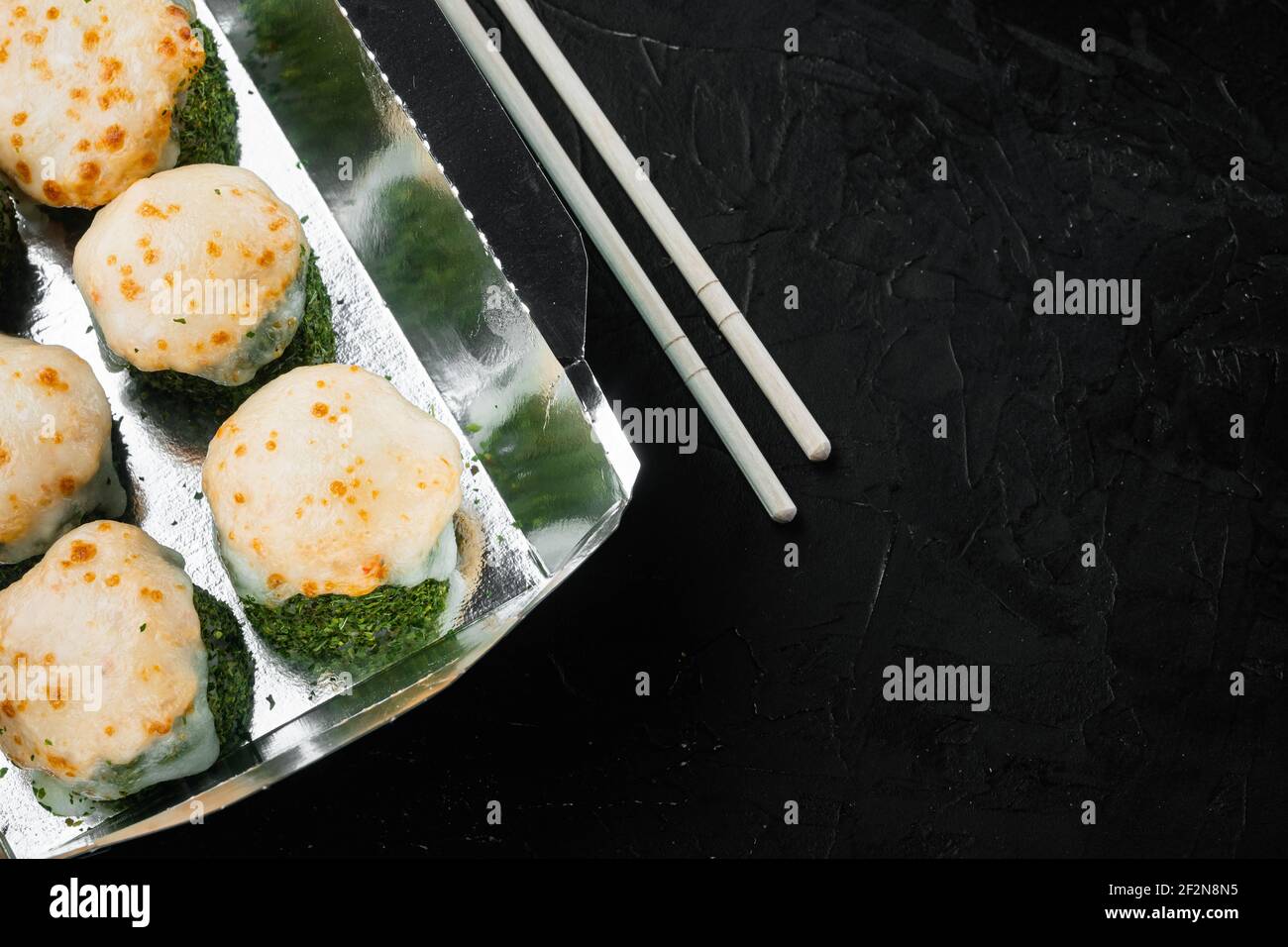 Leckere Sushi-Rollen in Einwegboxen Set, auf schwarzem Stein Hintergrund, Draufsicht flach legen, mit Copyspace und Platz für Text Stockfoto