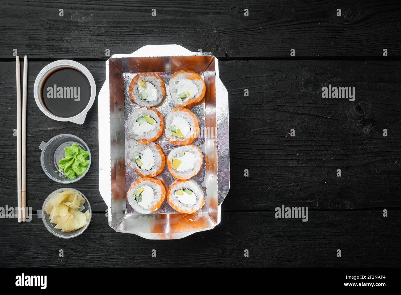 Japanisches Speisekonzept. Catering, verschiedene Arten von Sushi philadelphia Brötchen und gebackene Garnelen Rollen Set, auf schwarzem Holztisch Hintergrund, Draufsicht flach Stockfoto