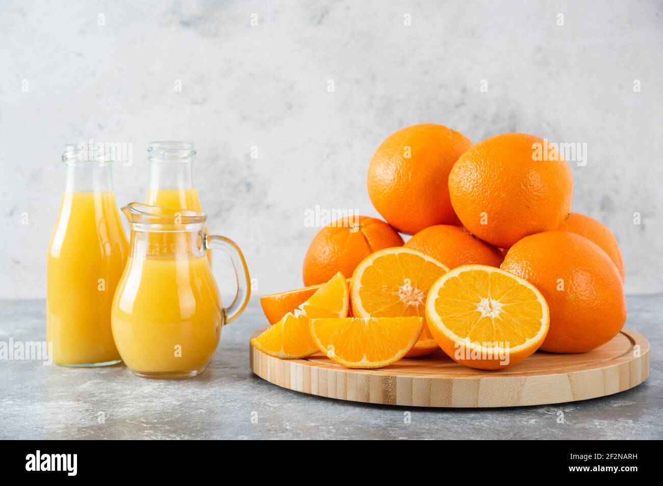 Ein Glas Krug Saft mit frischen Orangenfrüchten auf Steinhintergrund Stockfoto