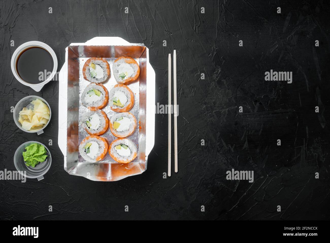 Sushi Roll Delivery Set, auf schwarzem Stein Hintergrund, Draufsicht flach legen, mit Copyspace und Platz für Text Stockfoto