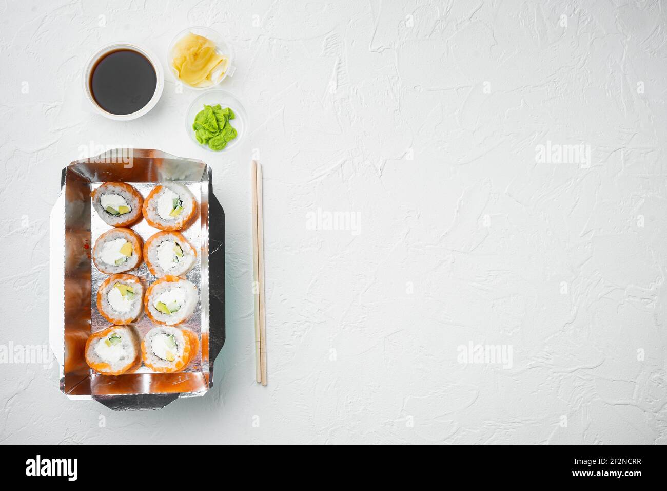 Leckere Sushi-Rollen in Einwegboxen Set, auf weißem Stein Hintergrund, Draufsicht flach legen, mit Copyspace und Platz für Text Stockfoto