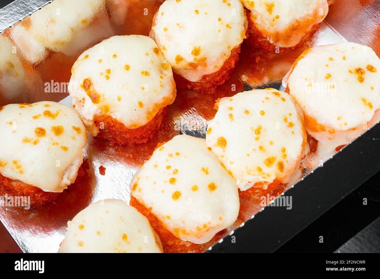 Sushi-Brötchen zum Mitnehmen in Behältern, philadelphia-Brötchen und gebackene Garnelenrollen auf schwarzem Stein-Hintergrund Stockfoto