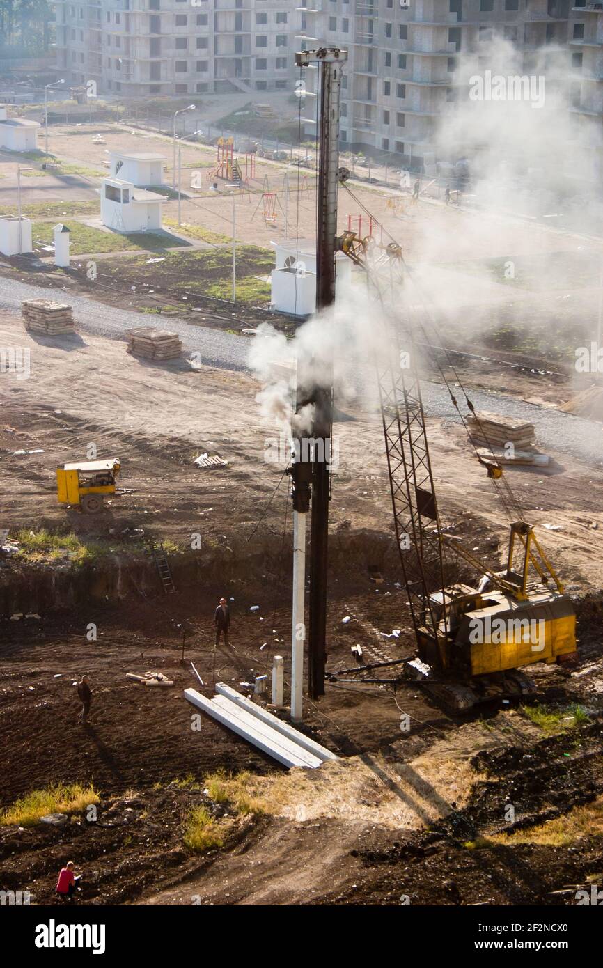 Fahren der Grundpfähle eines mehrstöckigen Gebäudes. Der Pfahlfahrer treibt die Pfähle zur Gründung des Hauses in den Boden Stockfoto