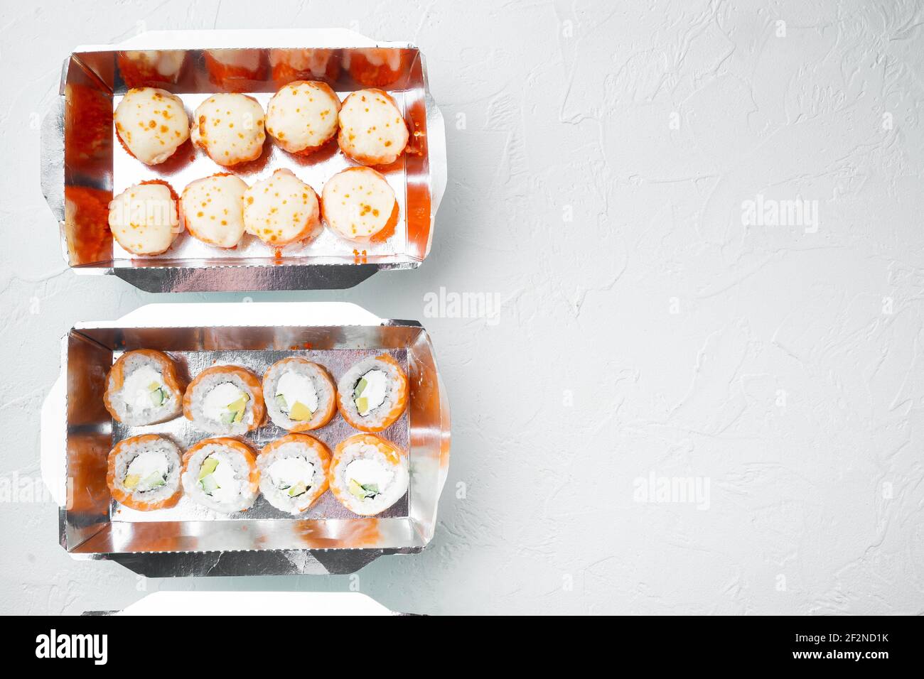 Leckere Sushi-Rollen in Einwegboxen Set, auf weißem Stein Hintergrund, Draufsicht flach legen, mit Copyspace und Platz für Text Stockfoto