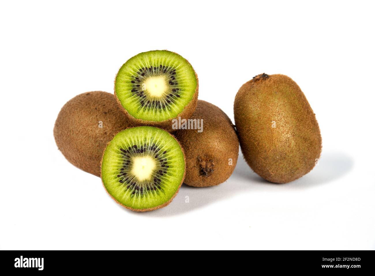 Ganze Kiwi-Früchte und halbe Kiwi-Früchte auf einem weißen Hintergrund Stockfoto