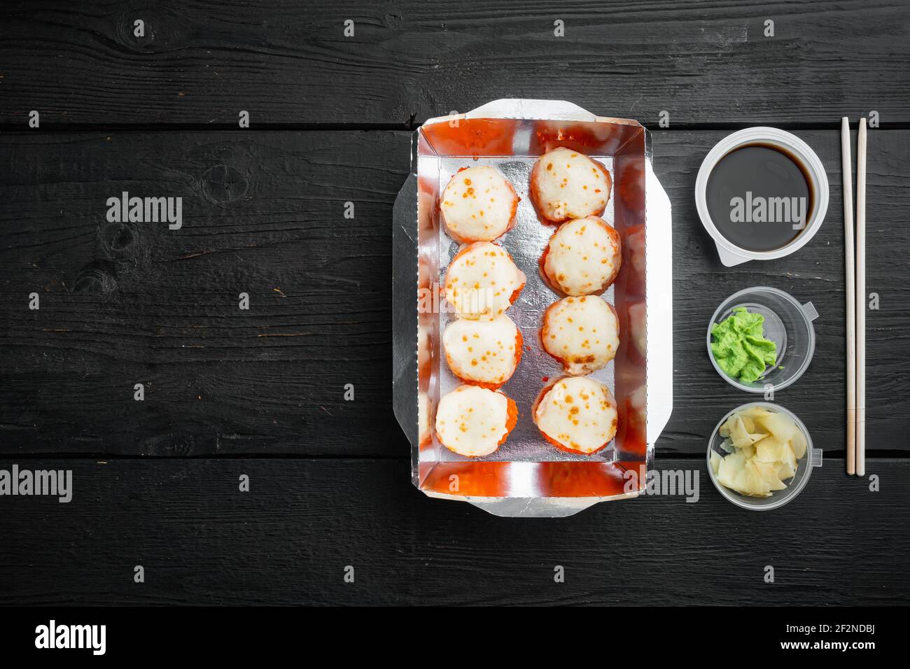 Sushi Roll Delivery Set, auf schwarzem Holztischhintergrund, Draufsicht flach liegend, mit Copyspace und Platz für Text Stockfoto