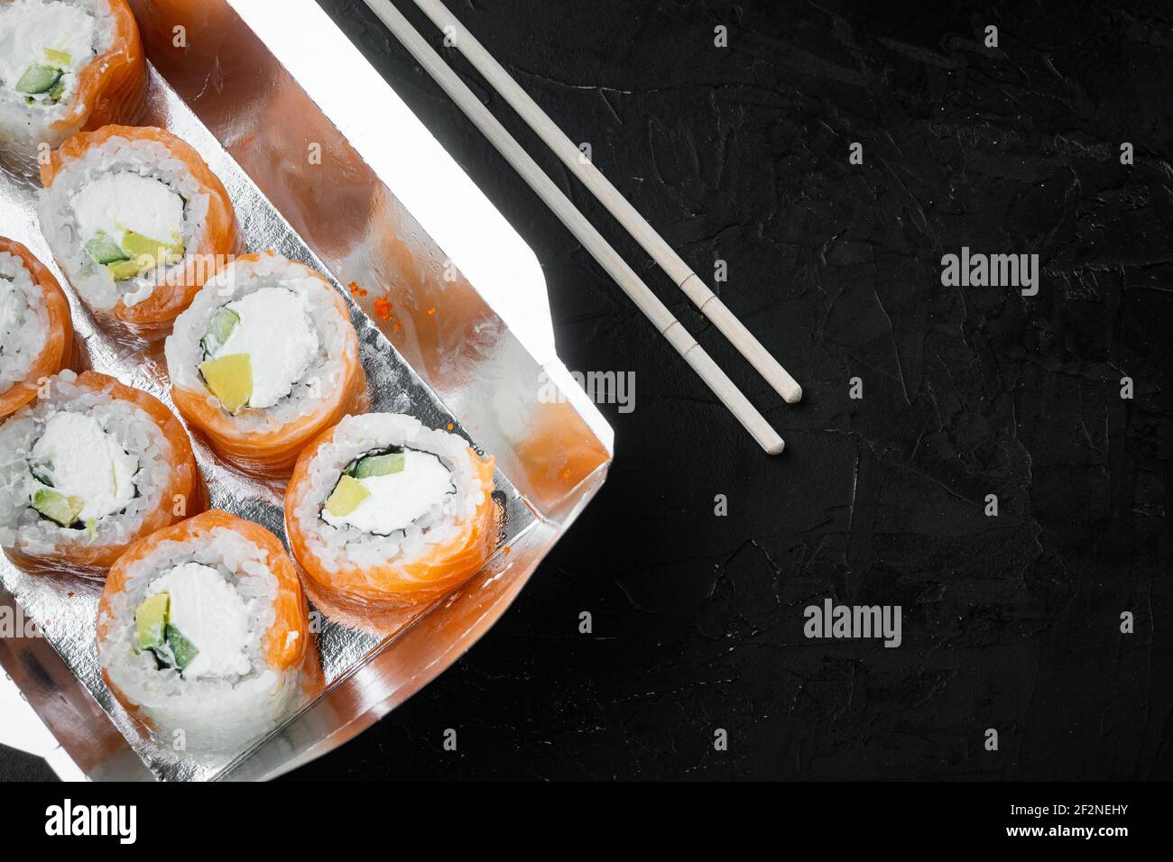 Japanisches Speisekonzept. Catering, verschiedene Arten von Sushi philadelphia Brötchen und gebackene Garnelen Brötchen Set, auf schwarzem Stein Hintergrund, Draufsicht flach lag, w Stockfoto