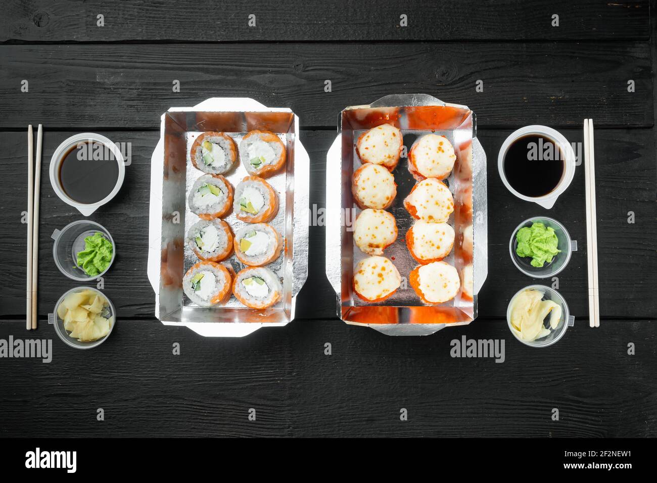 Japanisches Speisekonzept. Catering, verschiedene Arten von Sushi philadelphia Brötchen und gebackene Garnelen Rollen Set, auf schwarzem Holztisch Hintergrund, Draufsicht flach Stockfoto