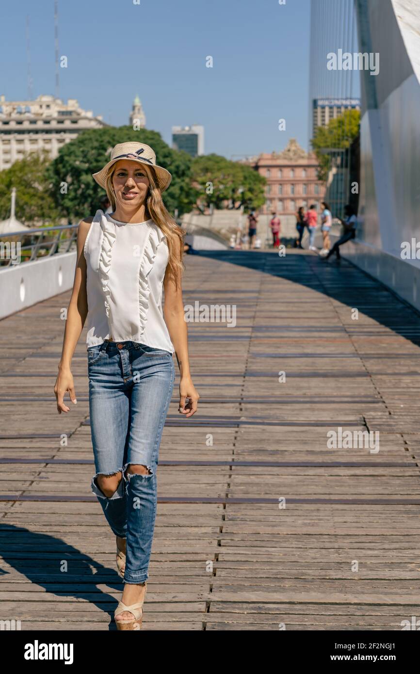 Schöne lateinische Frau, die auf einer Brücke mit Holzboden geht. Konzept Frauenstil. Stockfoto