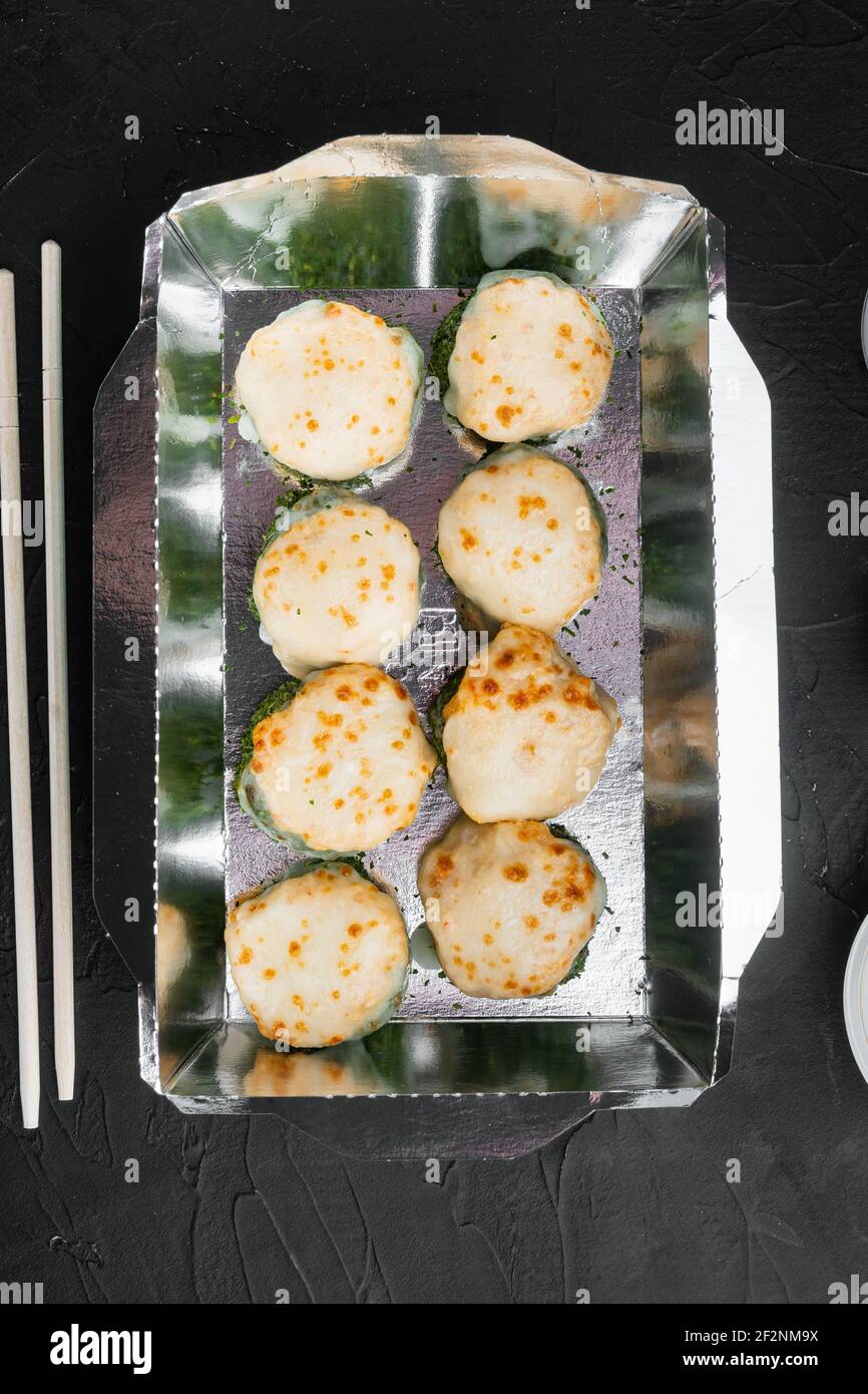 Vielfalt an verschiedenen Sushi und Brötchen, Lachs und Thunfisch im Lieferlebensmittelkonzept, auf schwarzem Stein Hintergrund, Draufsicht flach liegend Stockfoto