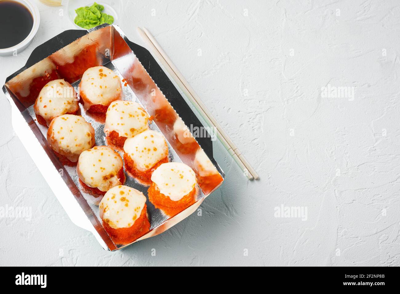 Sushi-Brötchen zum Mitnehmen in Behältern, philadelphia-Brötchen und gebackene Garnelenrollen Set, auf weißem Stein-Hintergrund, mit Textraum und Platz für Text Stockfoto