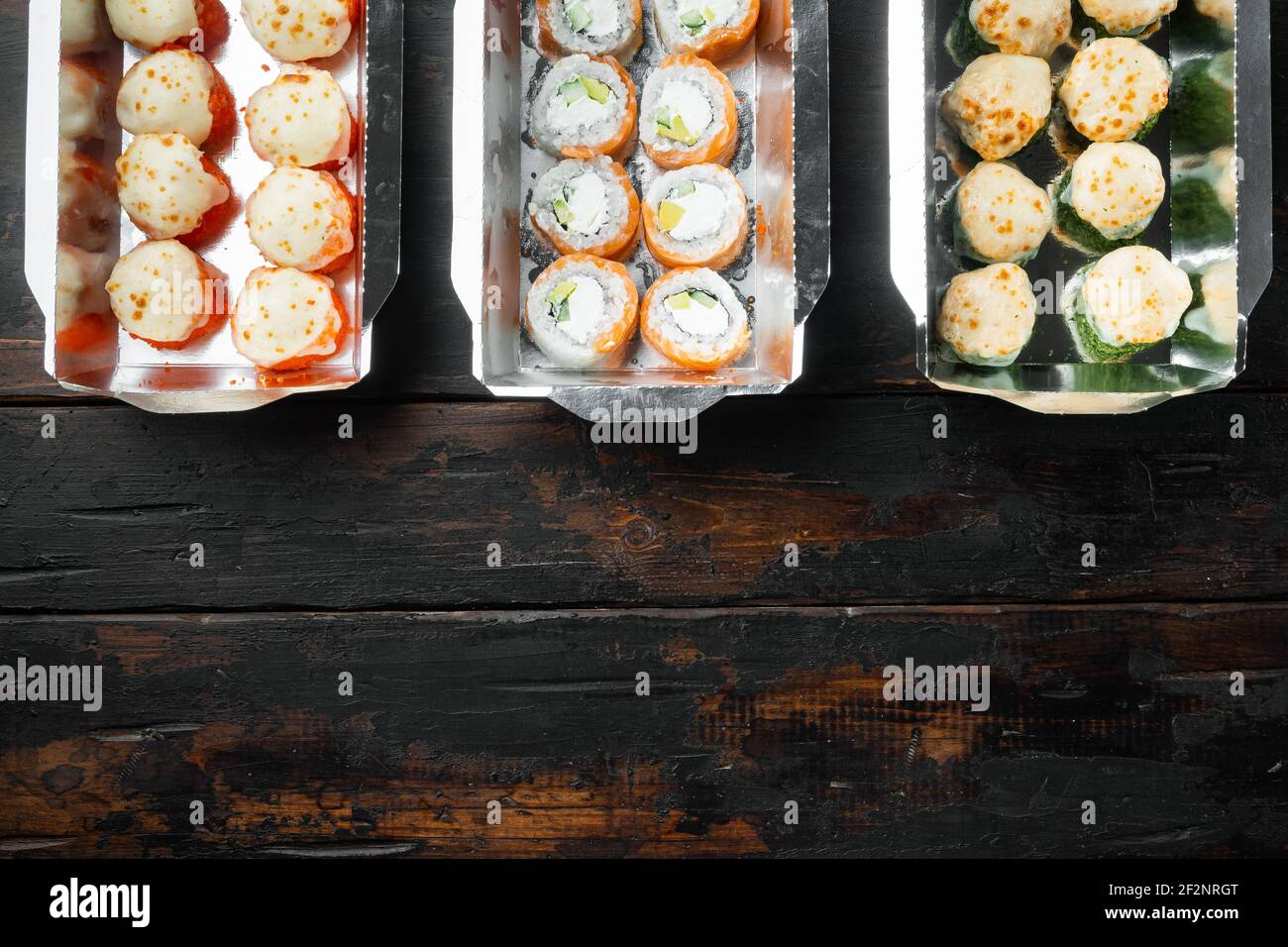 Set von Sushi-Rollen in Lieferung Food-Box-Set, auf alten dunklen Holztisch Hintergrund, Draufsicht flach legen, mit Copyspace und Platz für Text Stockfoto