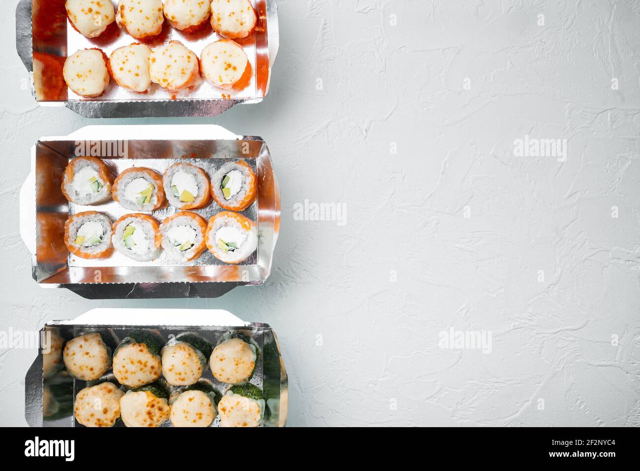 Set von Sushi-Rollen in Lieferung Food-Box-Set, auf weißem Stein Hintergrund, Draufsicht flach legen, mit Copyspace und Platz für Text Stockfoto