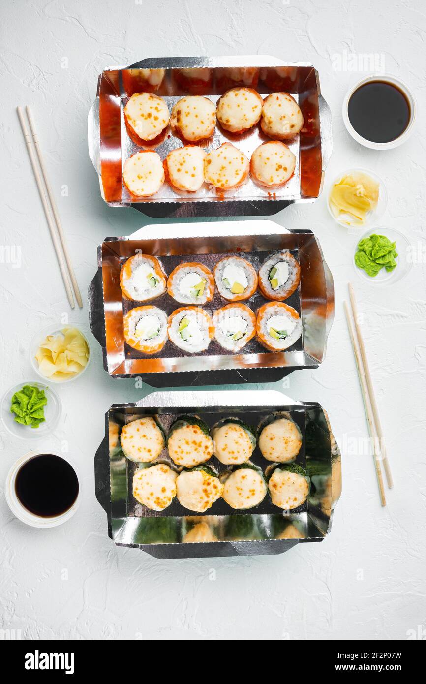 Sushi-Rollen im Takeaway-Container-Set, auf weißem Steinhintergrund, Draufsicht flach liegend Stockfoto