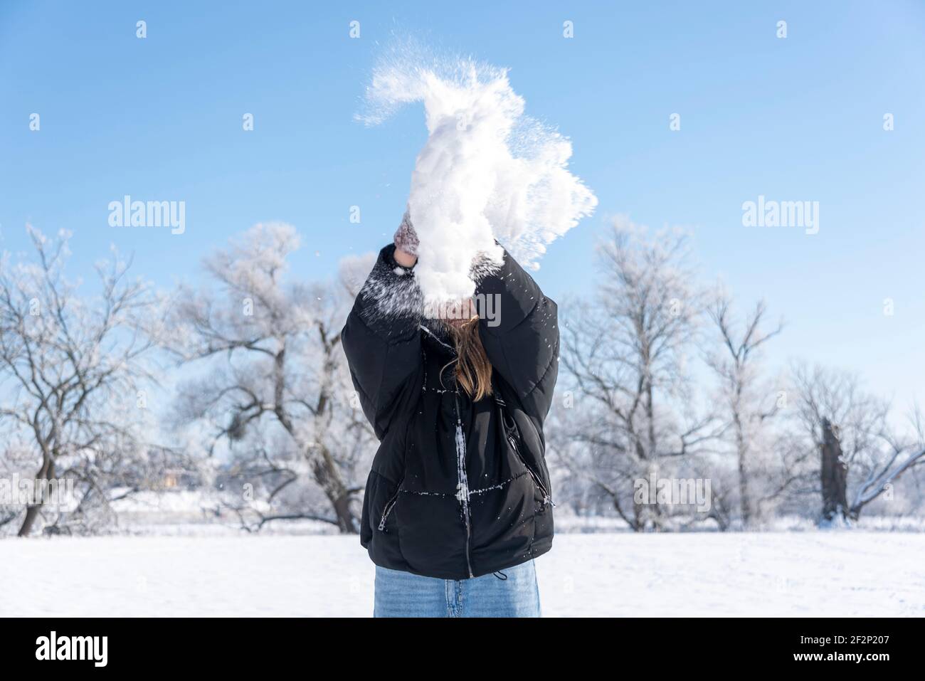 Ein Mädchen wirft Schnee in die Luft. Stockfoto
