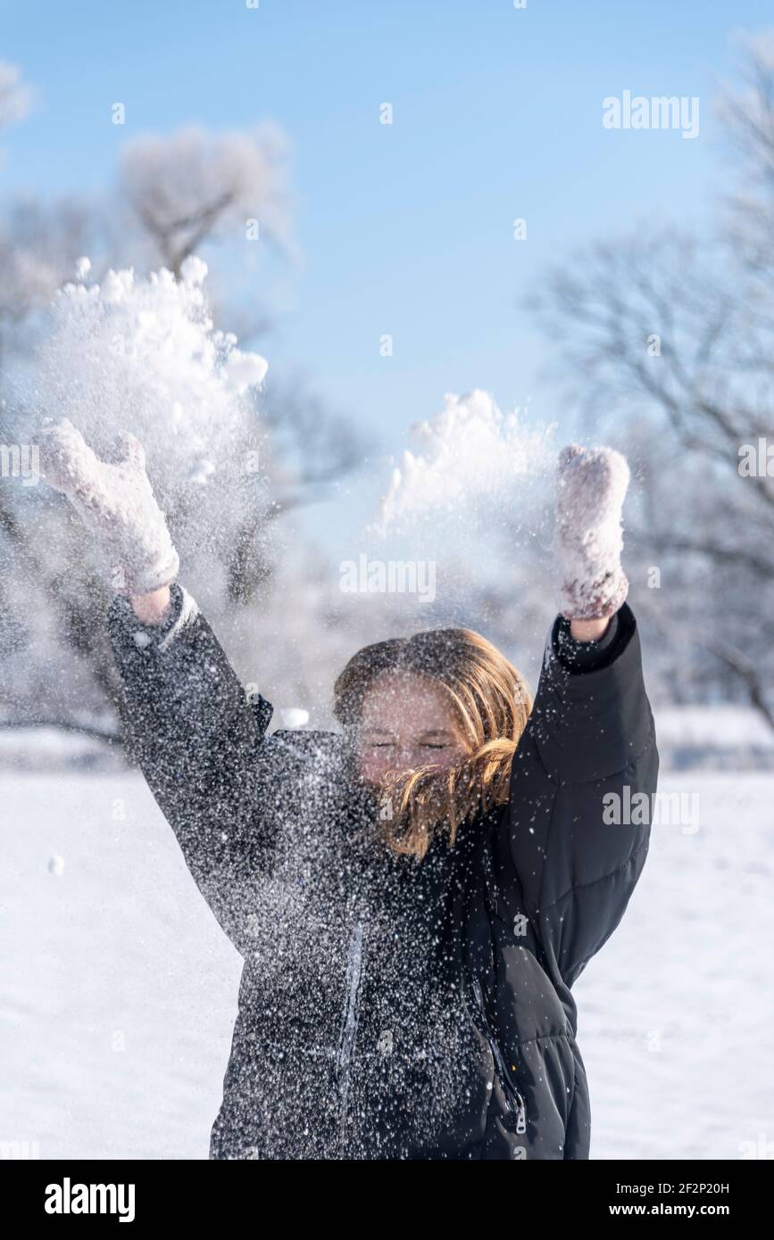 Ein Mädchen wirft Schnee in die Luft. Stockfoto