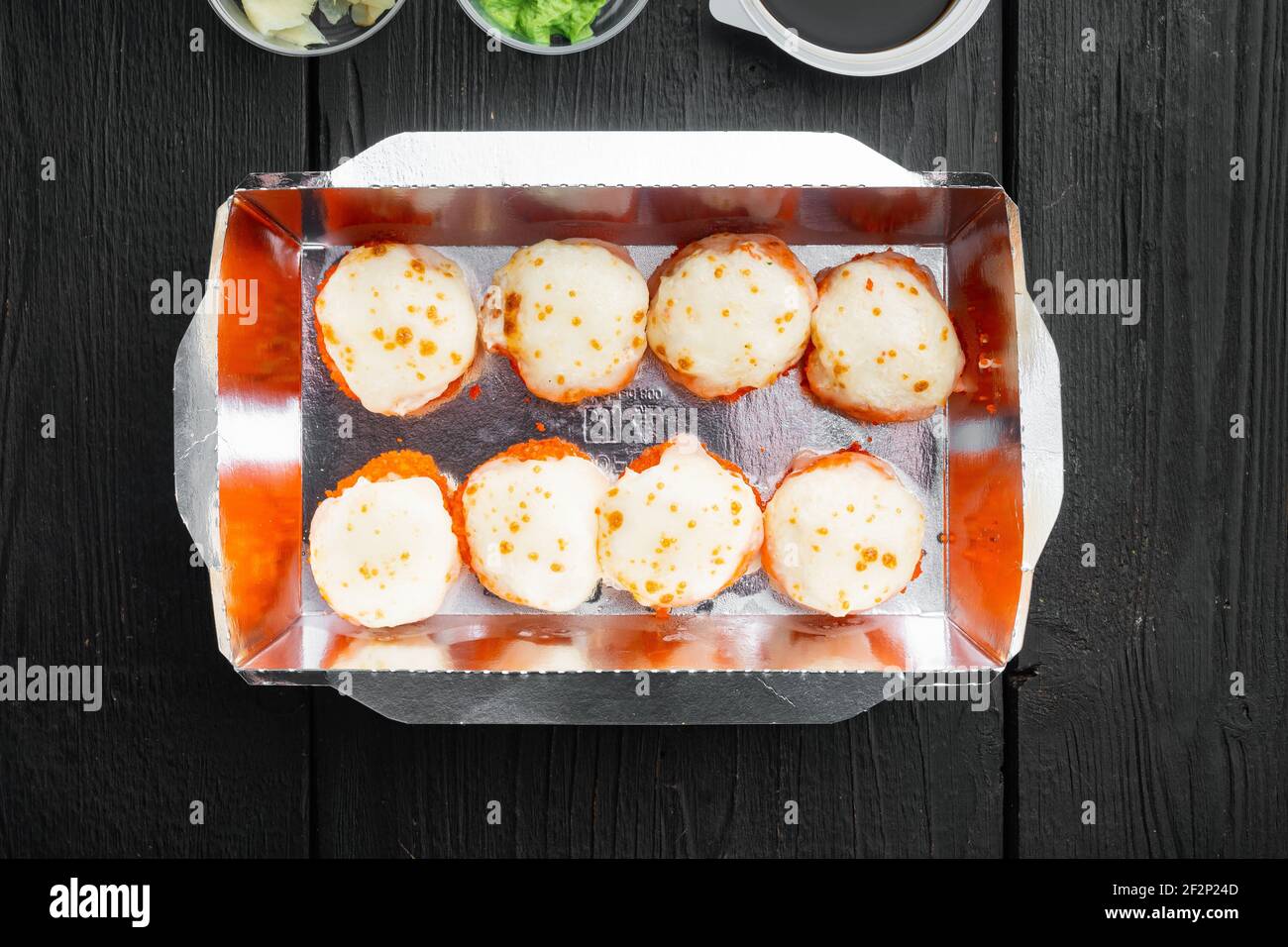 Set von Sushi-Rollen in Lieferung Food-Box-Set, auf schwarzem Holztisch Hintergrund, Draufsicht flach legen Stockfoto