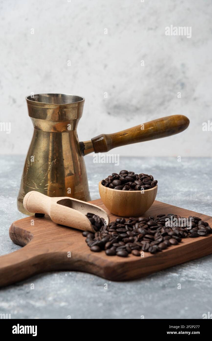 Dunkel geröstete Kaffeebohnen und Kaffeemaschine auf Holzschnitt Platine Stockfoto